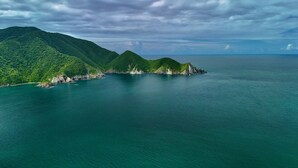 A coastal landscape with lush green hills and clear turquoise waters. - MISTICA Tayrona Cinto (Santa Marta)