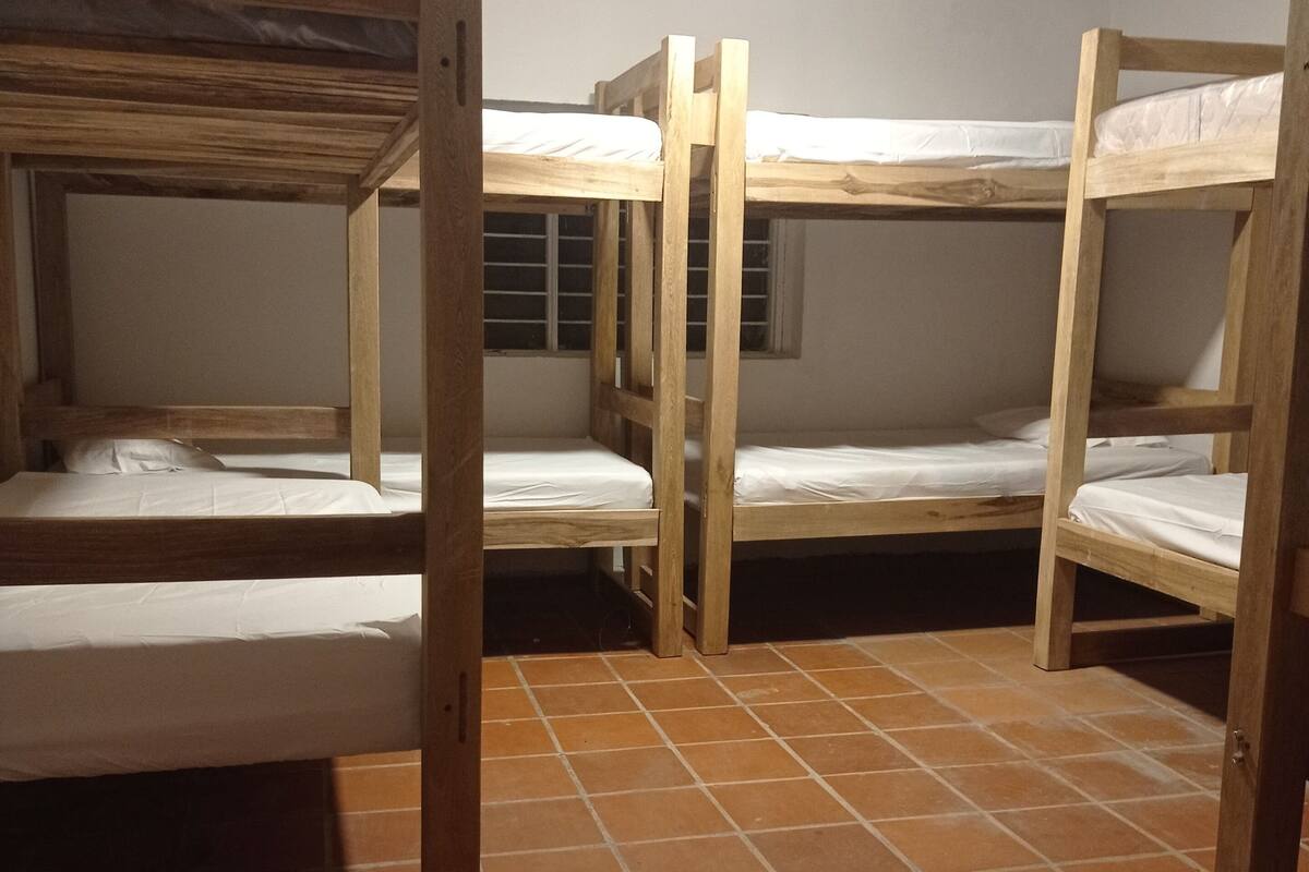 Un dormitorio con literas, piso de baldosas y una ventana con persianas.