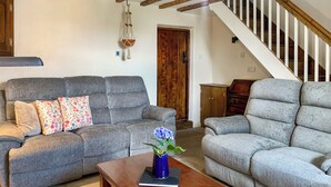 A living room with two grey sofas, a wooden coffee table, and a hanging macrame decoration. - 3 bedroom accommodation in Leek (Leek)