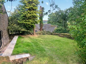 Un jardin bien entretenu, agrémenté d’un mur de pierres, d’une pelouse et de diverses espèces d’arbres et d’arbustes.