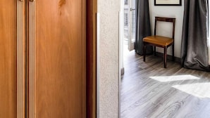 Een kamer met een houten garderobe, een stoel en een lijst met een foto aan de muur.
