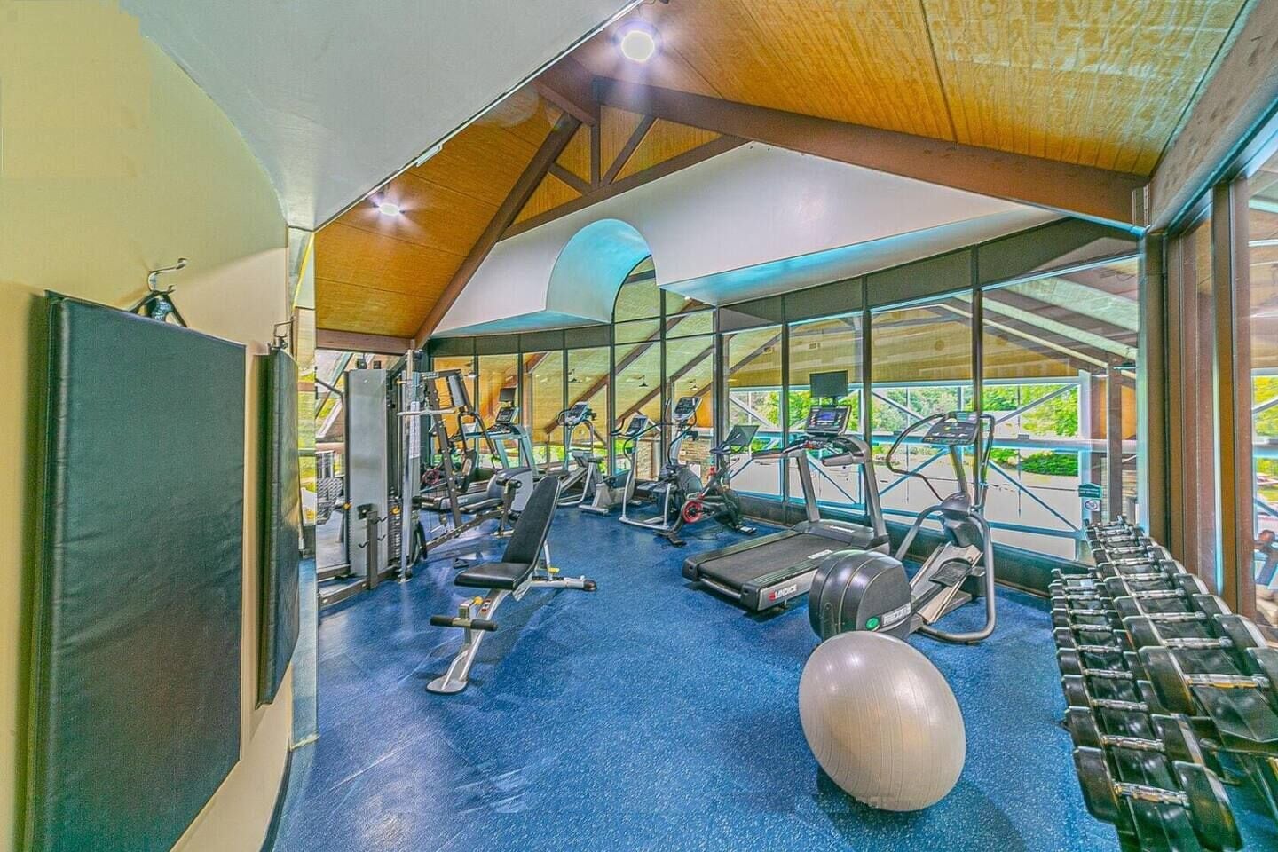 Une salle de sport équipée de divers appareils d’exercice, notamment des tapis de course, des appareils de musculation et des poids libres.
