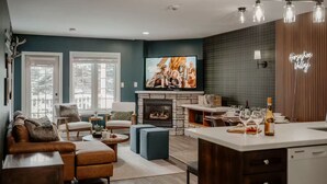 A modern living room with a fireplace, a television, and a dining area with a kitchen island.