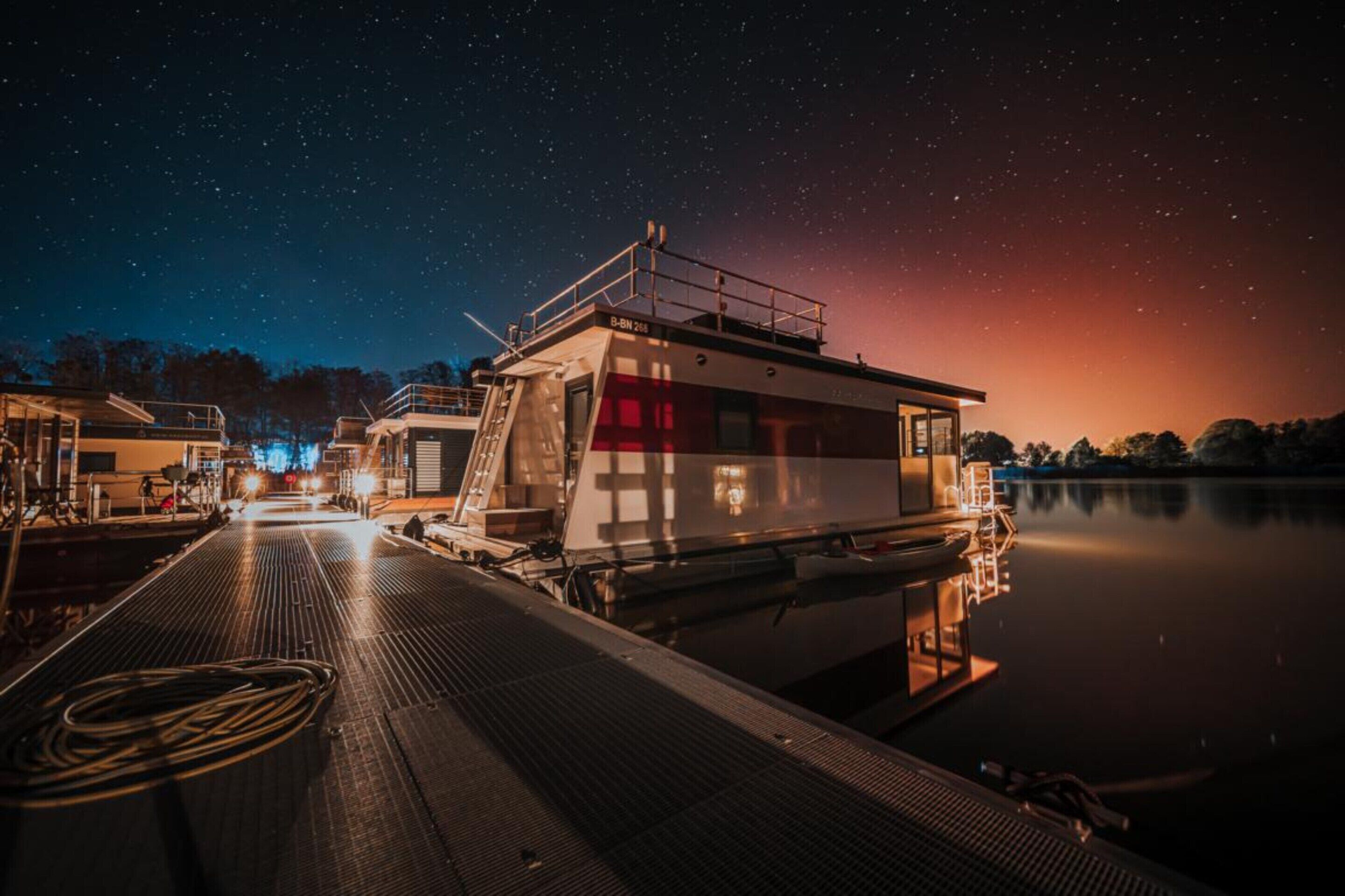 Un barco amarrado con cabina, cielo nocturno despejado y agua tranquila que refleja el barco.