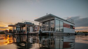 Une structure flottante moderne dotée d’une façade en verre, d’une bouée de sauvetage et d’une zone de pont.
