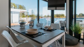 Un espace de restauration moderne avec une table dressée pour deux, donnant sur une piscine et un coin salon extérieur.