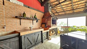 Une cuisine extérieure rustique avec des murs en briques, des poutres en bois et un toit de chaume.