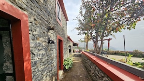 Un bâtiment en pierre avec des éléments décoratifs rouges, un étroit sentier et une vue sur le paysage.