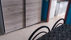 Ein Schlafzimmer mit einem Bett, einem Kleiderschrank und einer durch eine offene Tür sichtbaren Küche.