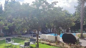 Eine Terrasse mit Pool, Sitzgelegenheiten im Freien und Blick auf einen üppigen Garten.