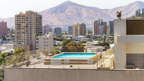 Ein Pool auf dem Dach mit Blick auf die Stadt und Berge im Hintergrund.