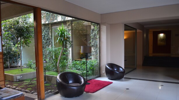 Ein modernes Interieur mit zwei schwarzen Stühlen, einem roten Teppich und einer Glastür, die in einen Garten führt.