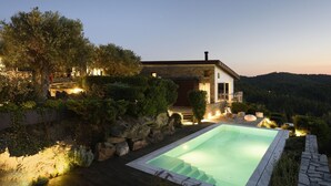 A modern house with a swimming pool, stone walls, and a view of the surrounding hills. - Villa Matelia Chalkidiki (Sithonia)