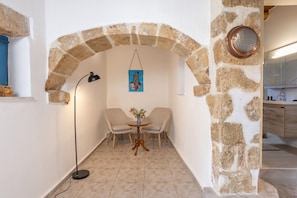 Cozy corner with a stone archway leading to a dining area, featuring a small table and two chairs.