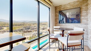 Un balcon avec vue sur une vallée, une piscine et un espace repas avec des tables et des chaises.