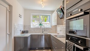 A modern kitchen with a built-in oven, a microwave, and a sink. - 2 bedroom accommodation in Brixham (Brixham)