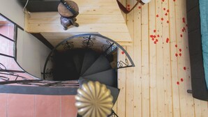 Eine Wendeltreppe mit Holzvertäfelung, ein kleines dekoratives Objekt auf der obersten Plattform und verstreute Rosenblätter auf dem Boden.