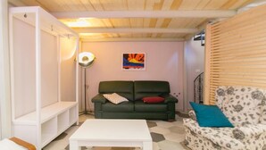 Ein gemütliches Wohnzimmer mit einem grünen Sofa, einem weißen Couchtisch und einem gemusterten Sessel.