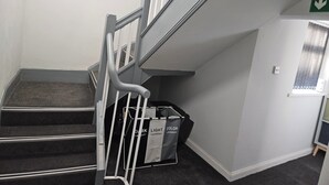 Un escalier doté d’une rampe, de marches recouvertes de moquette et d’un panneau fixé au mur indiquant une sortie.