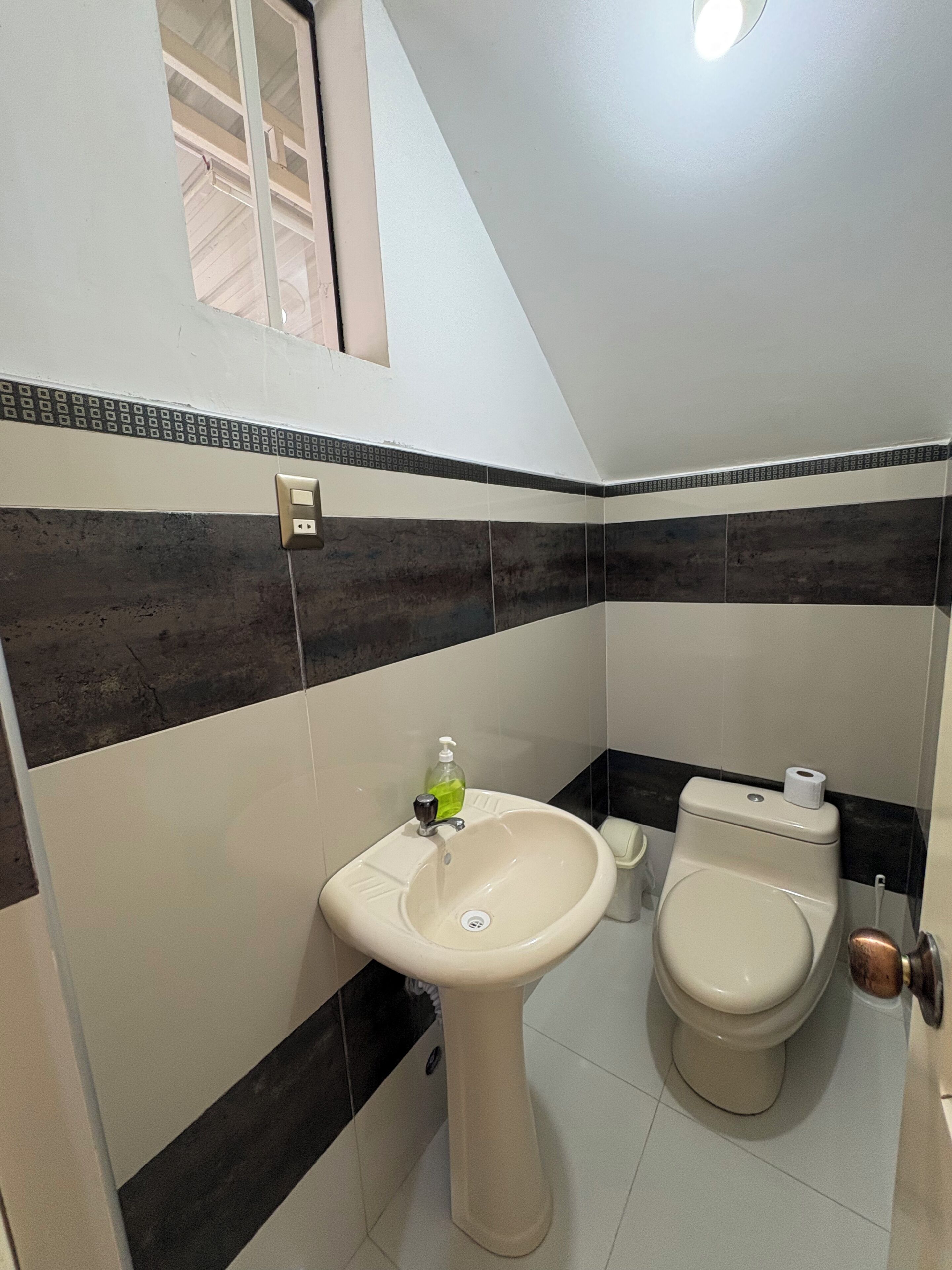 A bathroom with a sink, toilet, and a window above the sink.