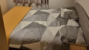 A compact bedroom with a bed, a small shelf, and a curtain. - Southview 48 Morningside (Skegness)