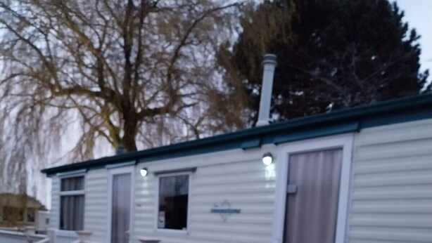 A mobile home with a front porch, a small deck, and a ramp leading to the entrance. - Southview 48 Morningside (Skegness)