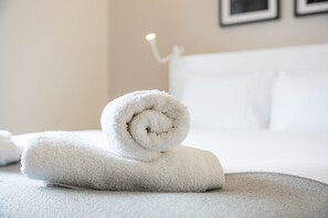 Toalla blanca e impecable sobre una cama en una habitación de hotel.
