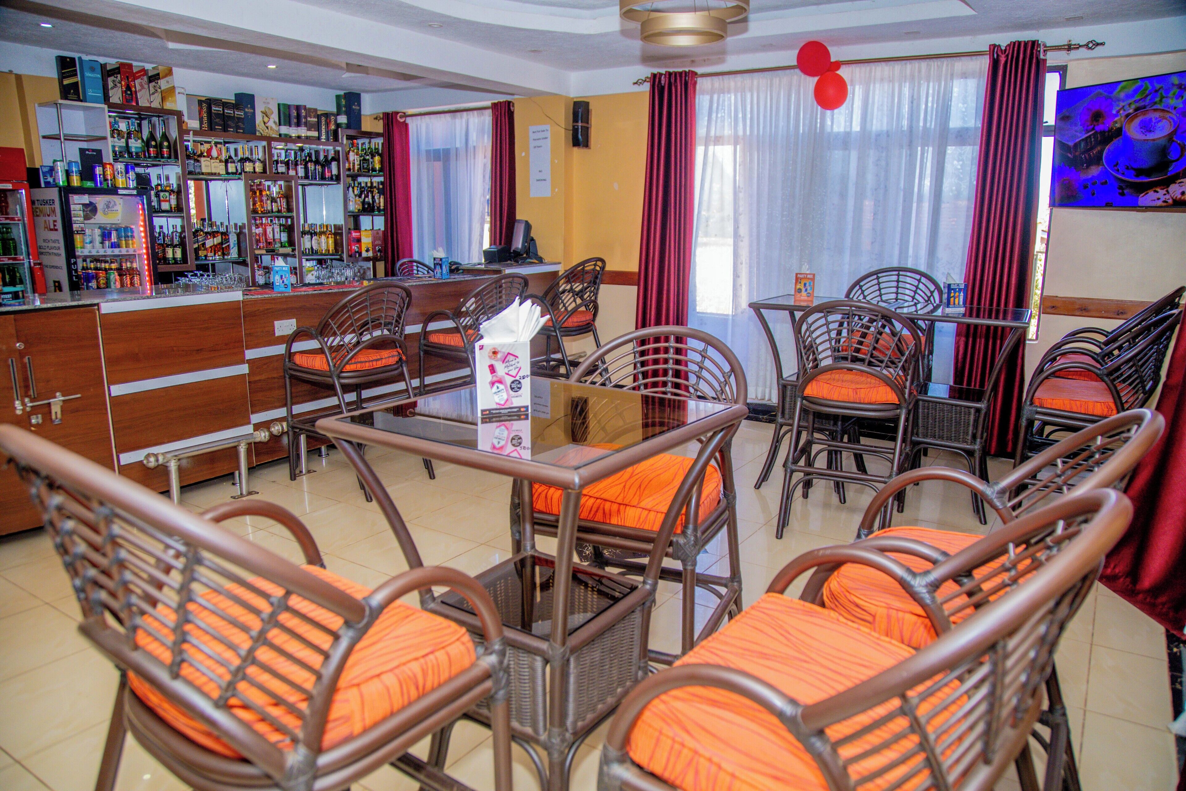 A bar area with wicker furniture and a variety of bottles and glasses.