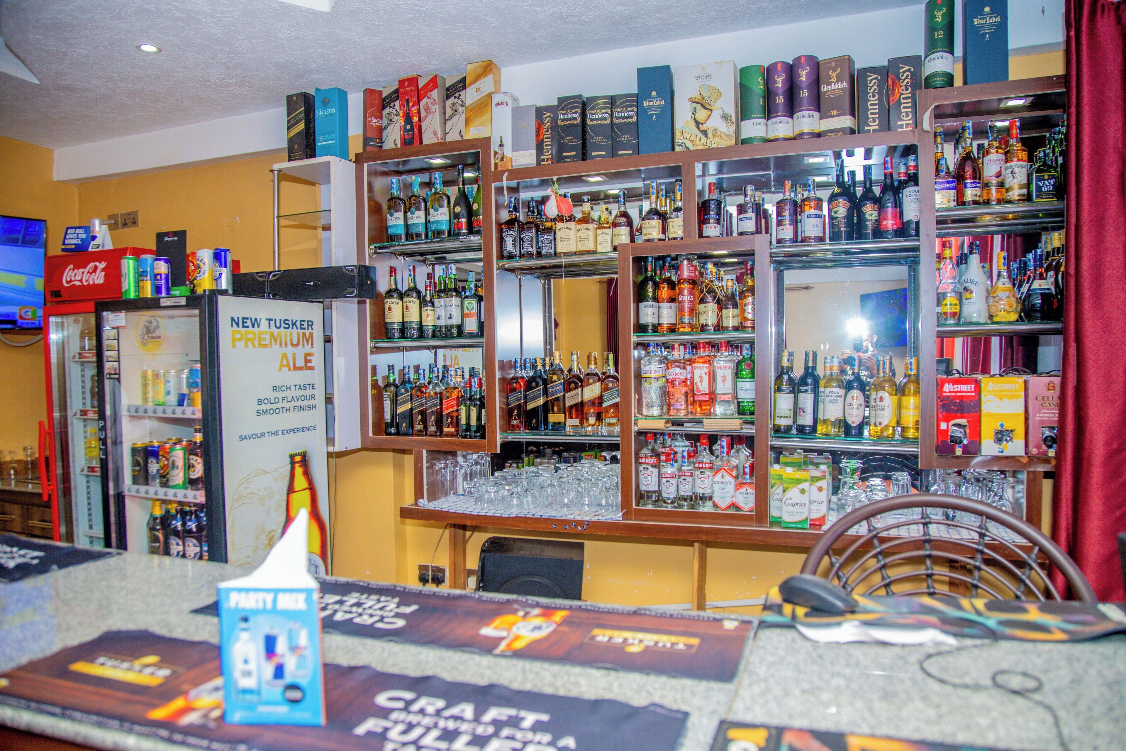 A bar area with shelves stocked with various liquor bottles and glasses.