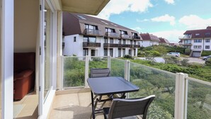 A balcony with a table and chairs, overlooking a residential area with multiple apartment buildings. - Apartment Near Belgian Coast With Terrace (Koksijde)