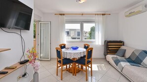 A modern living room with a dining table, sofa, TV, and air conditioning unit. - Bright Apartment in Medolino (Medulin)