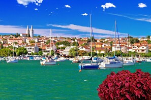 Un port de plaisance avec des bateaux amarrés, une ville aux bâtiments aux toits rouges et, au loin, un clocher d’église imposant.