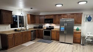 A modern kitchen with wooden cabinets, stainless steel appliances, and a large refrigerator. - 3BR 1.5Ba - Private Hot Tub & Game Room!! 2 Pets stay free! (Ocean Shores)
