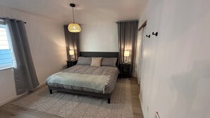 A modern bedroom with a bed, two bedside tables with lamps, a patterned rug, and a ceiling light fixture. - 3BR 1.5Ba - Private Hot Tub & Game Room!! 2 Pets stay free! (Ocean Shores)