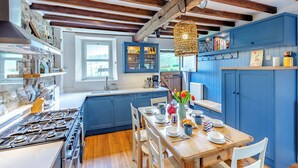 A modern kitchen with blue cabinets, a wooden dining table, and a stone wall backsplash. - 4 bedroom accommodation in Sedbergh (Sedbergh)