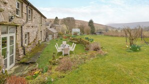 A stone building with a garden and a table with chairs. - 4 bedroom accommodation in Sedbergh (Sedbergh)