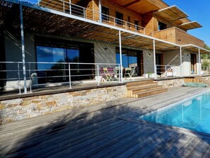 A modern house with a swimming pool, stone walls, and wooden deck. - Charming house in the greenery - Downtown Porto-Vecchio (Porto-Vecchio)