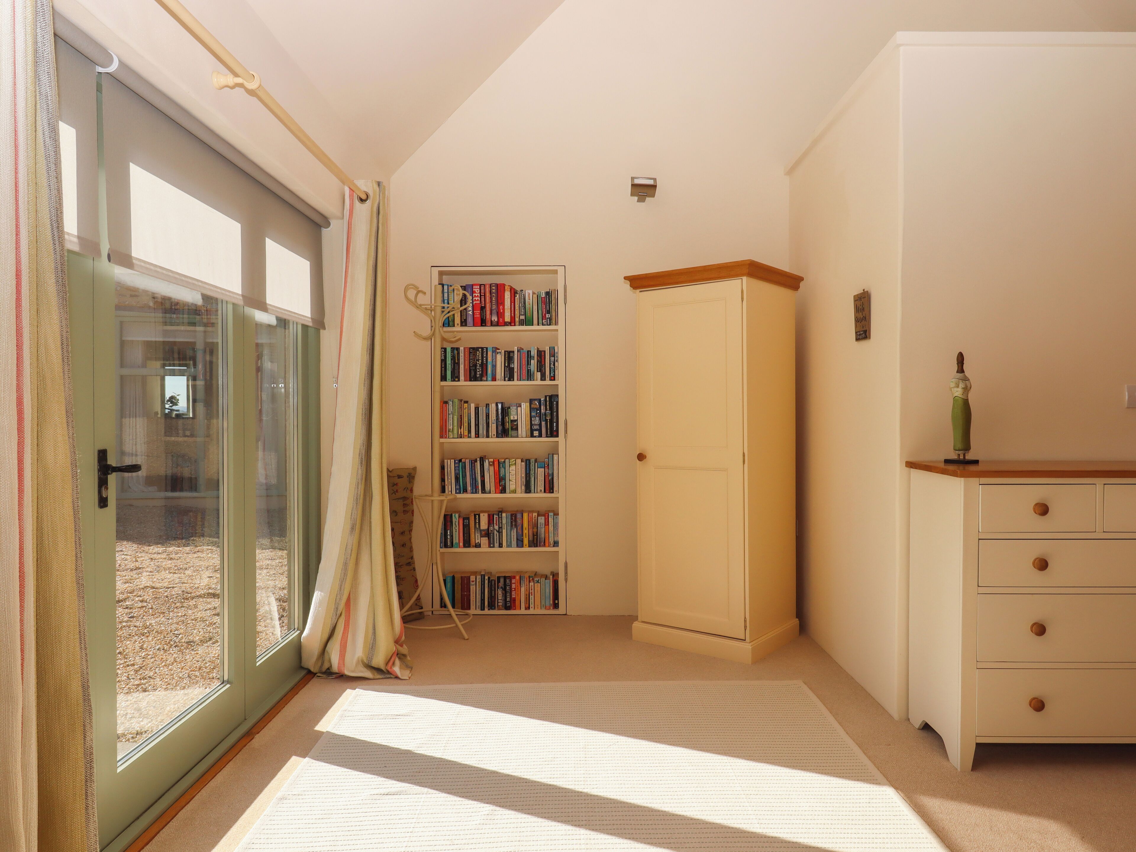 A room with a sliding glass door, a bookshelf, a cabinet, and a dresser.