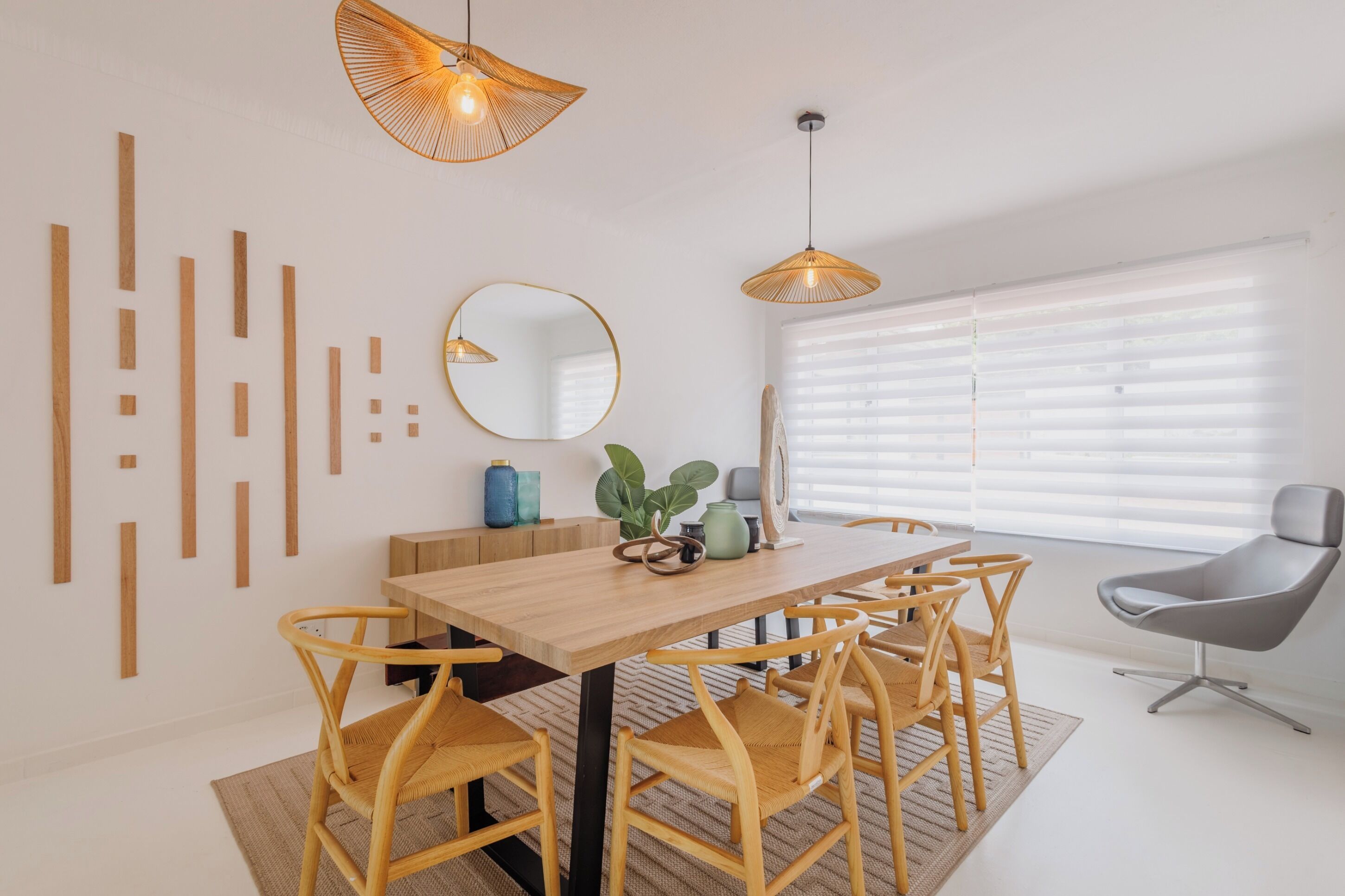 Un comedor con una mesa de madera, sillas de mimbre e iluminación colgante.