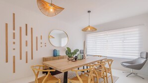 Un coin repas avec une table en bois, des chaises en osier et des luminaires suspendus.