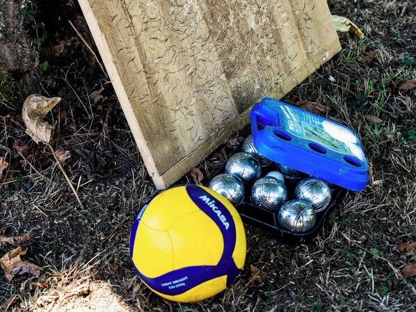A yellow and blue volleyball, a blue container, and several metallic balls on the ground. - Domaine de Fontenay (Fontenay-sur-Vègre)