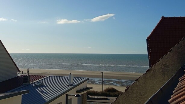 A view of the beach from a building with a sloped roof and a metal railing. - Nice T3 with balcony - 5 mn from the beach (Merlimont)