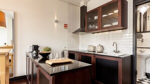 A modern kitchen with dark wood cabinets, a black countertop, and a white tiled backsplash. - Studio Apartment Next to Clerigos Tower (Porto)