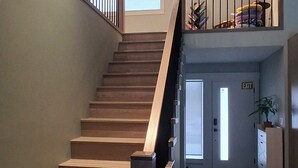 Eine Holztreppe mit Handlauf, die zu einer Zwischenebene mit einer Tür mit der Aufschrift 'EXIT' führt.