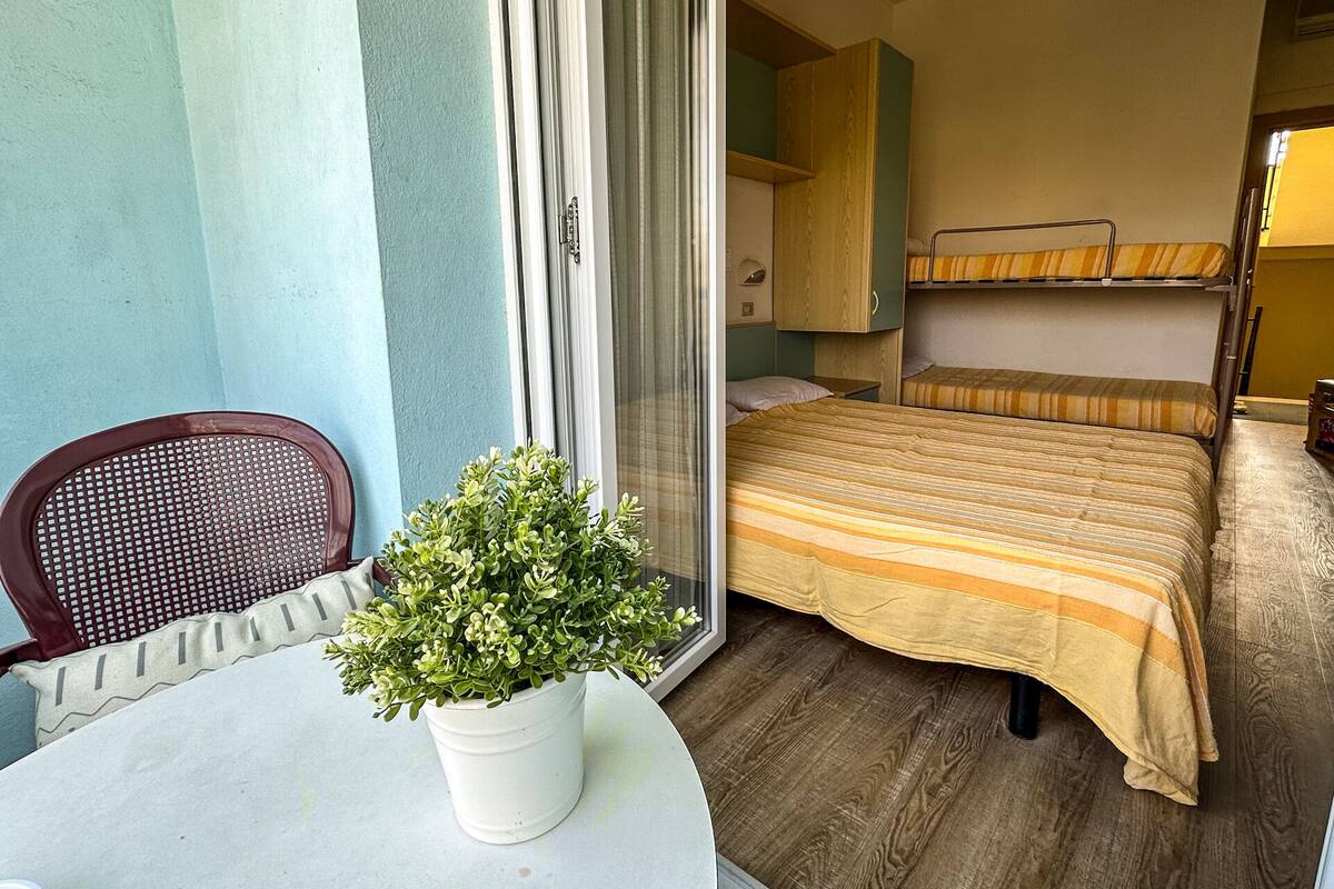 Habitación de hotel compacta con una cama individual, una mesita con planta en maceta y una silla.
