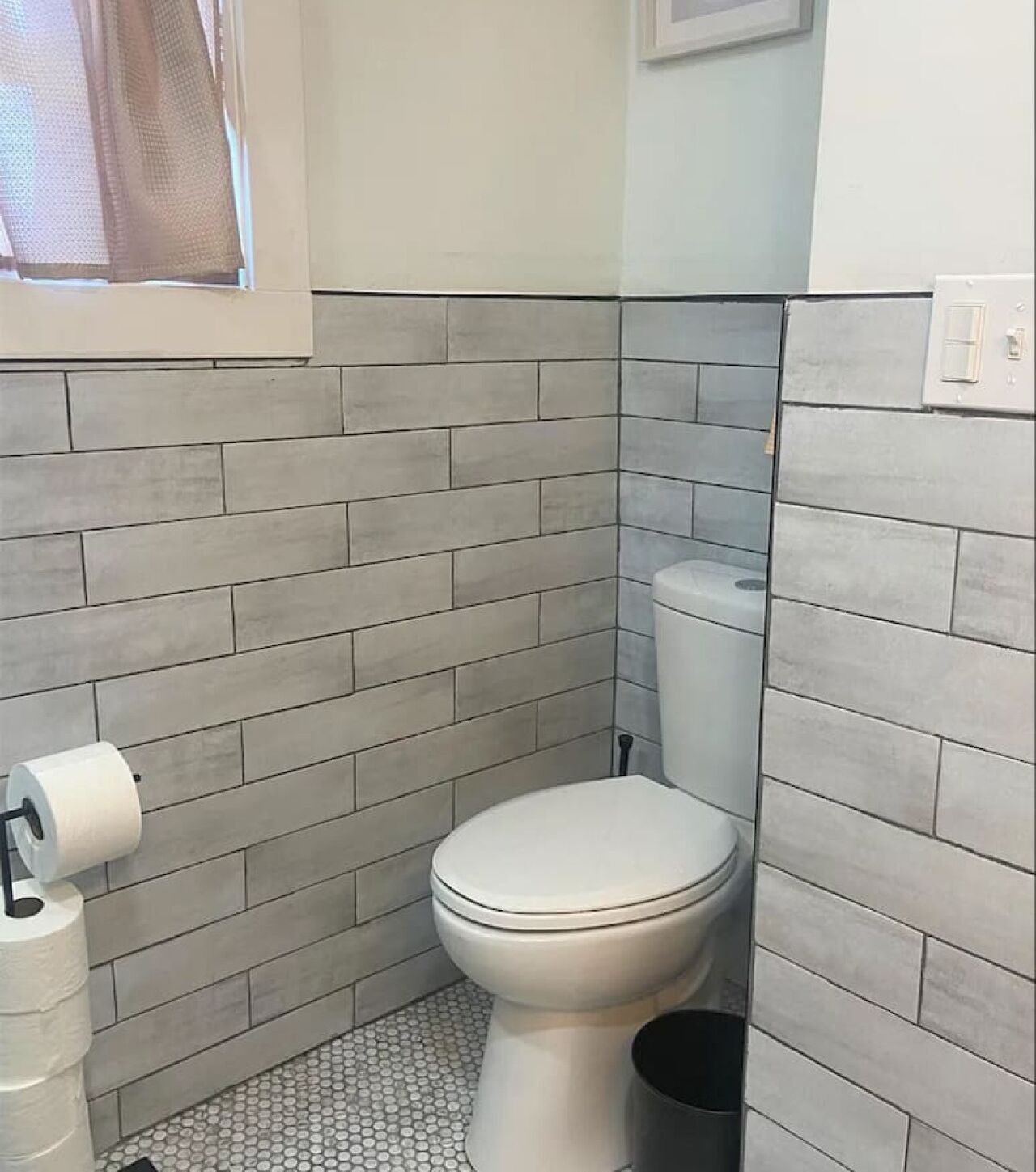 Un bagno con un WC, un porta carta igienica e un cestino.