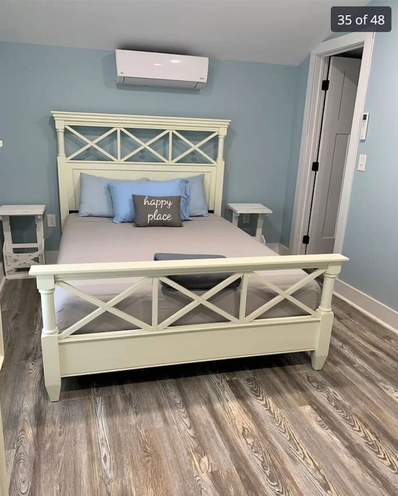 Un dormitorio con una cama, dos mesitas de noche, un armario y aire acondicionado instalado en la pared.