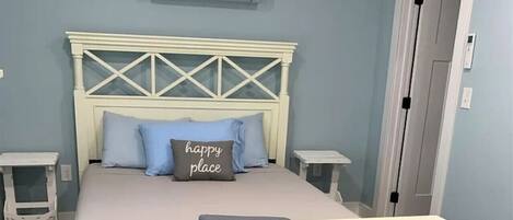 Un dormitorio con una cama, dos mesitas de noche, un armario y aire acondicionado instalado en la pared.