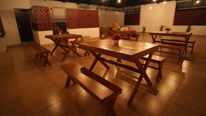 A spacious indoor dining area with multiple wooden tables and benches, a decorative partition, and a tiled floor.