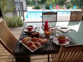 Una mesa preparada para el desayuno con cruasanes, una taza roja y un vaso de agua.